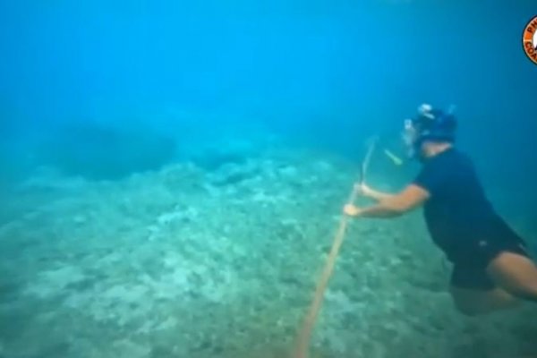 Un buzo filipino ayuda a eliminar con un cuchillo una barrera flotante instalada por China en el mar de China Meridional