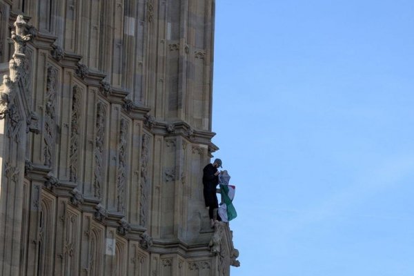 Un hombre se encarama a la torre del Big Ben enarbolando la bandera palestina